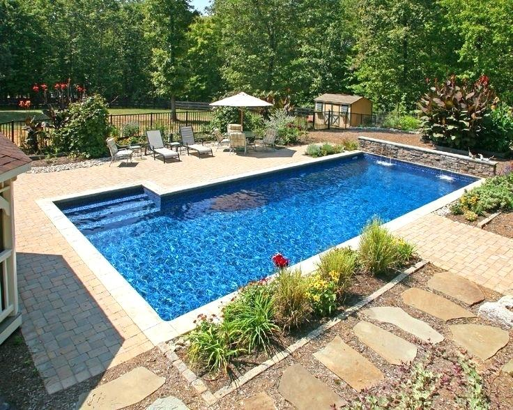 A rectangular inground pool with stone coping and landscaped garden