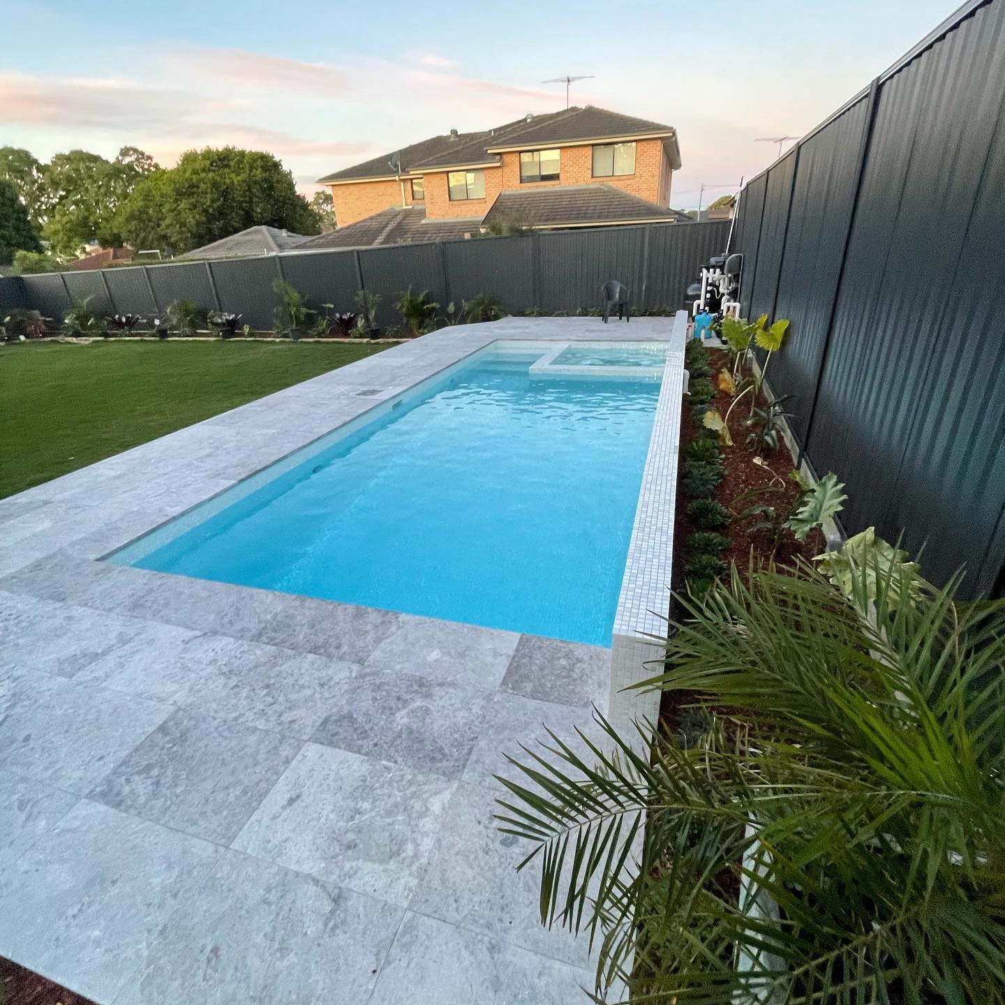 A residential lap pool with an attached spa and landscaped surrounds