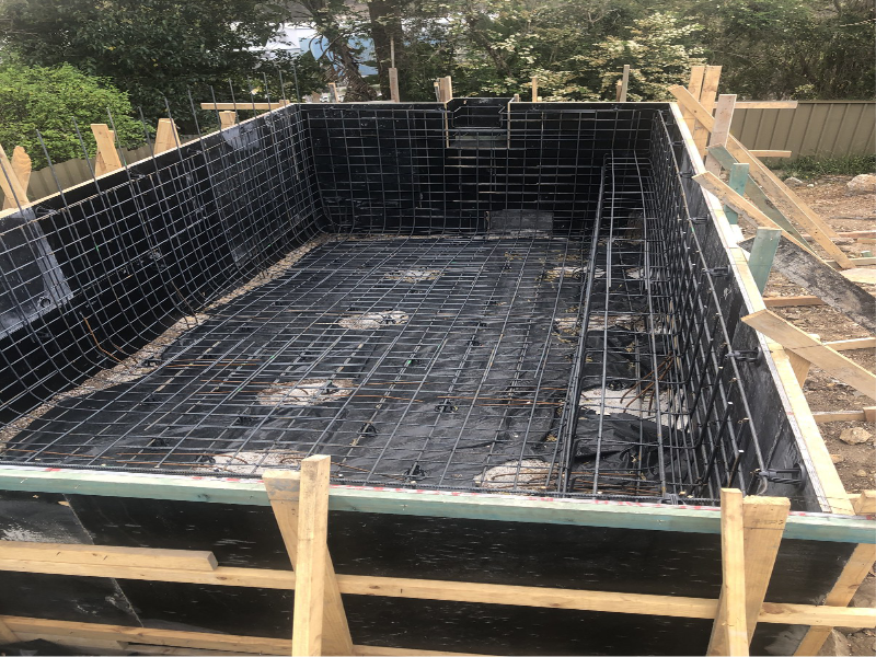 A concrete pool shell being formed and steel fixed on site